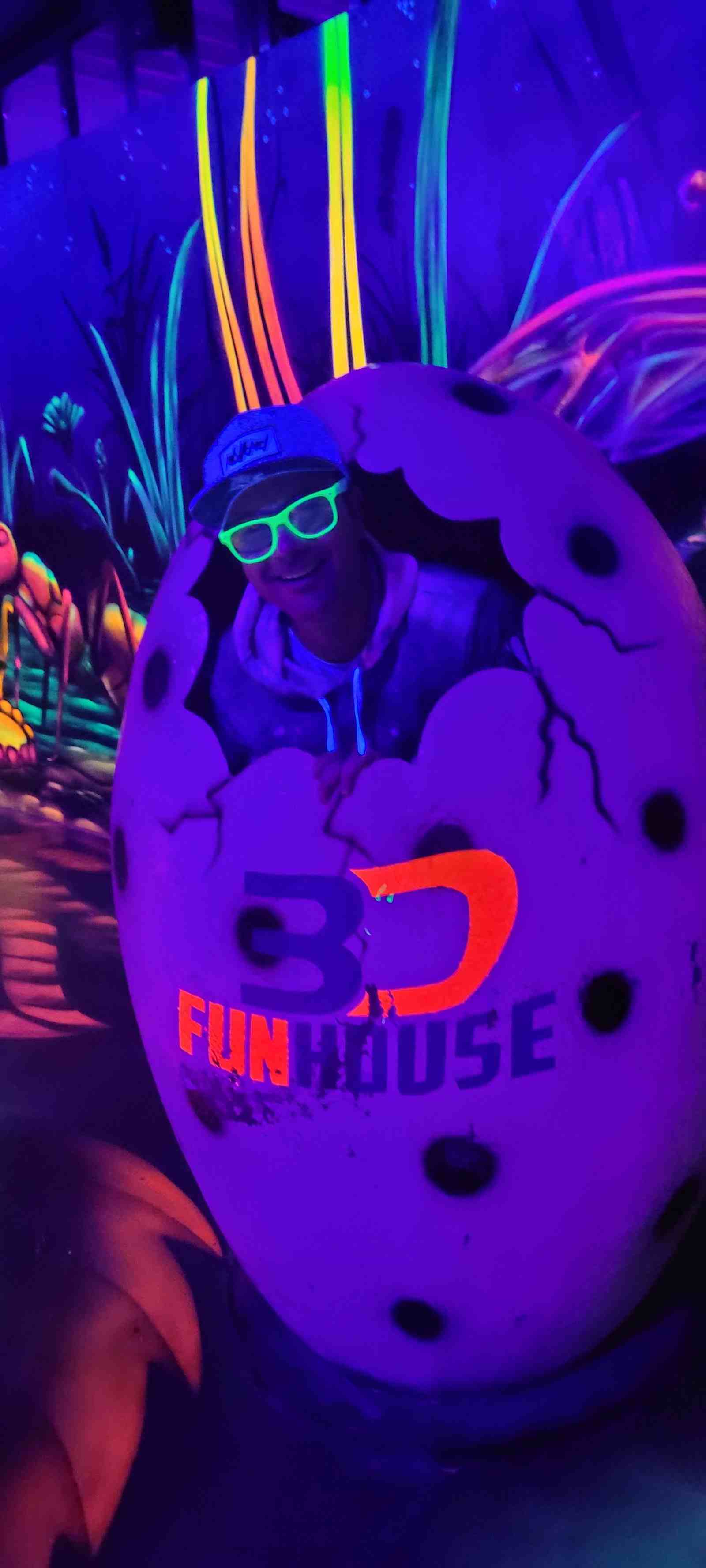 Lächelnder Mann mit Cap und grüner Brille schaut aus einem bemalten Ei mit dem Schriftzug 3D Funhouse